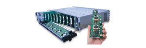 A hand holding a circuit board in front of a device with multiple slots.